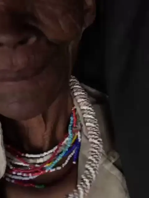 Close portrait of an elder wearing traditional beadwork during a documentary interview