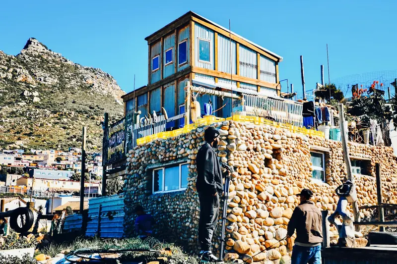 A self-built home of stone and salvaged timber on a hillside above the sea