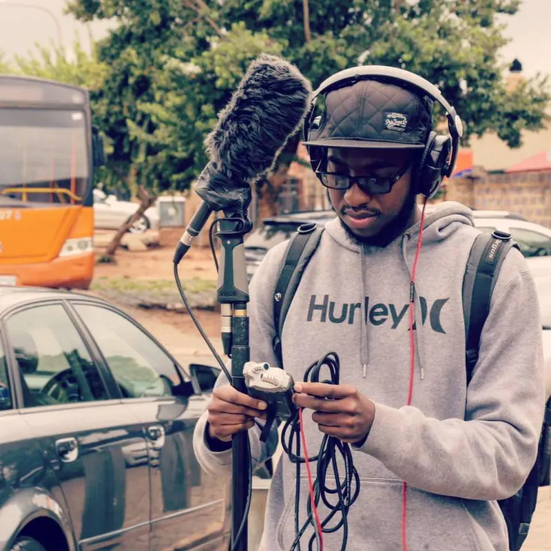 Recording location sound with boom microphone and headphones on a street